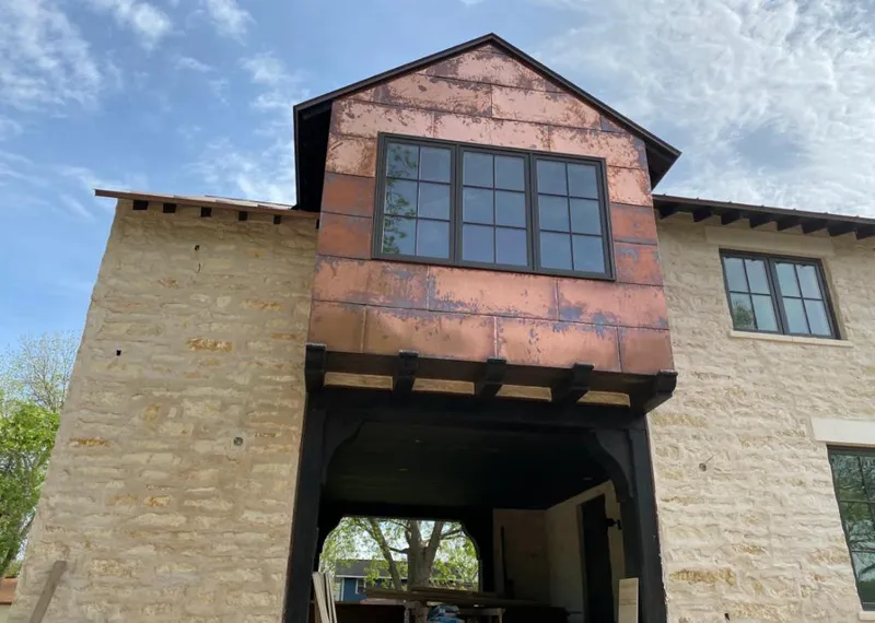 Copper metal panel facade on a stone building for Roof Repair in Heartland