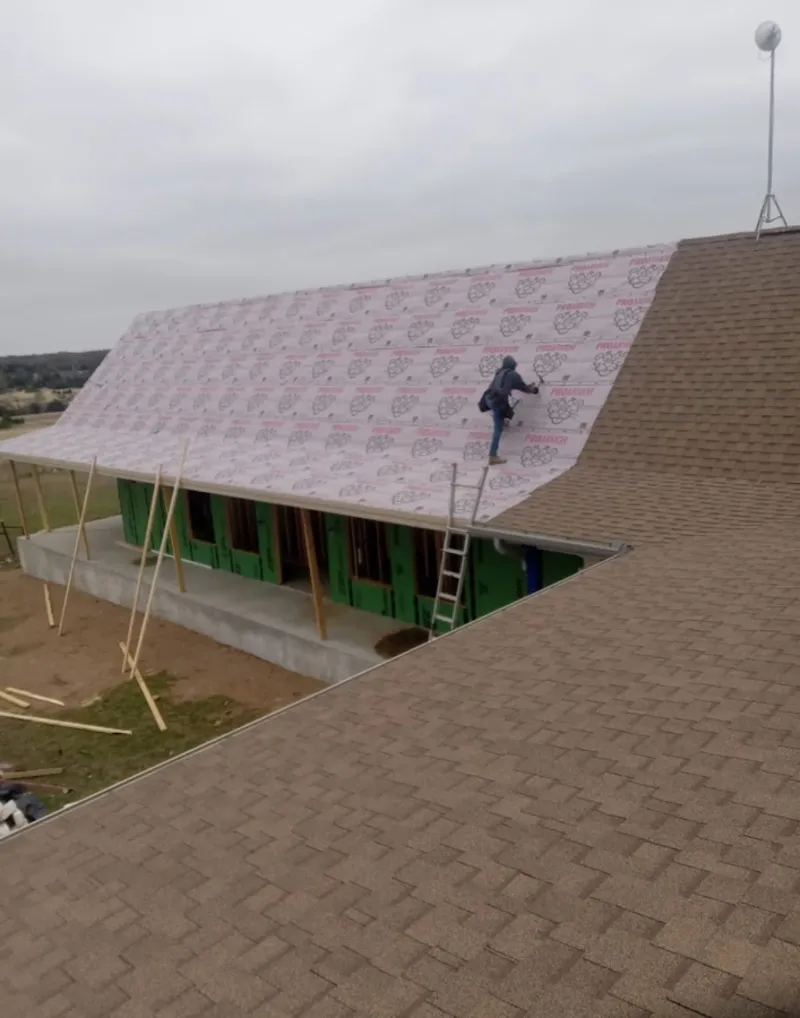 Worker preparing underlayment for a metal roof installation in Heartland